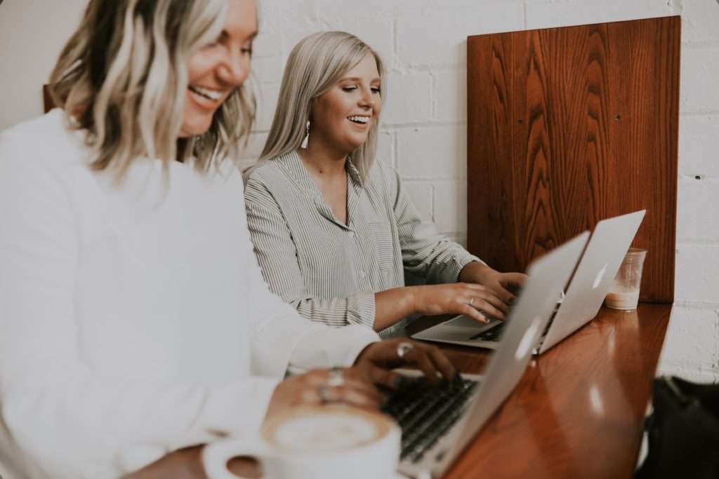 zwei lächelnde blonde Frauen am Laptop